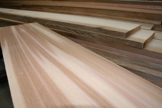 Wide clear old-growth Western Red Cedar board with additional milled cedar lumber in the workshop