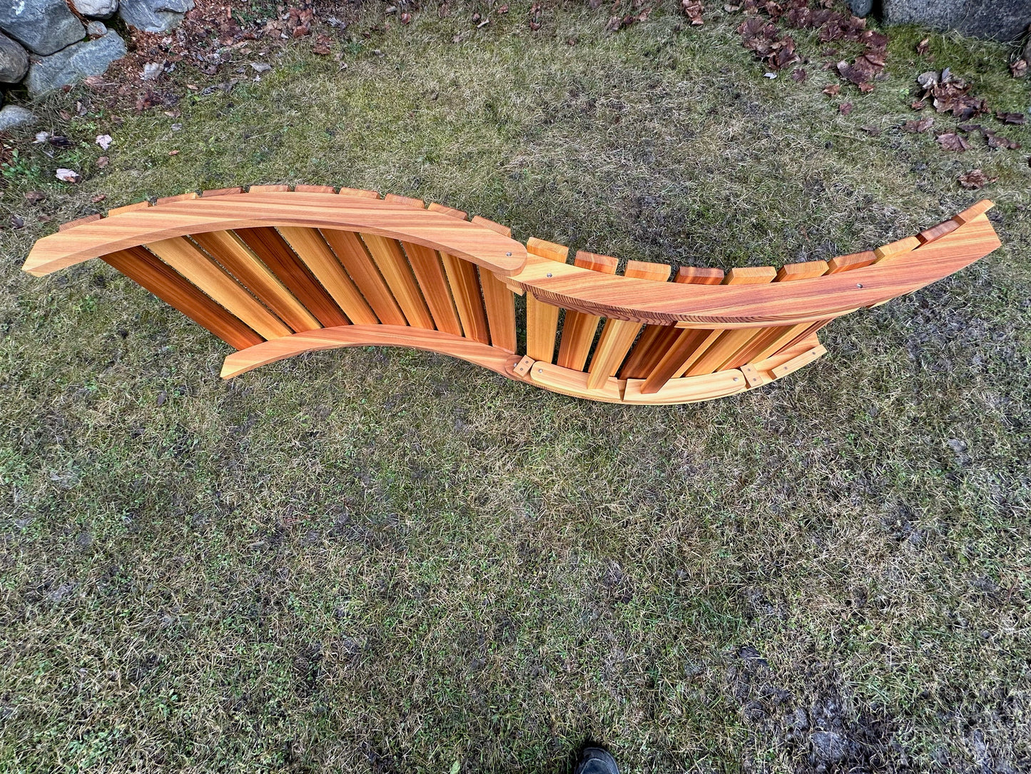 Underside view of a cedar folding lounger showing the curved frame and slat construction