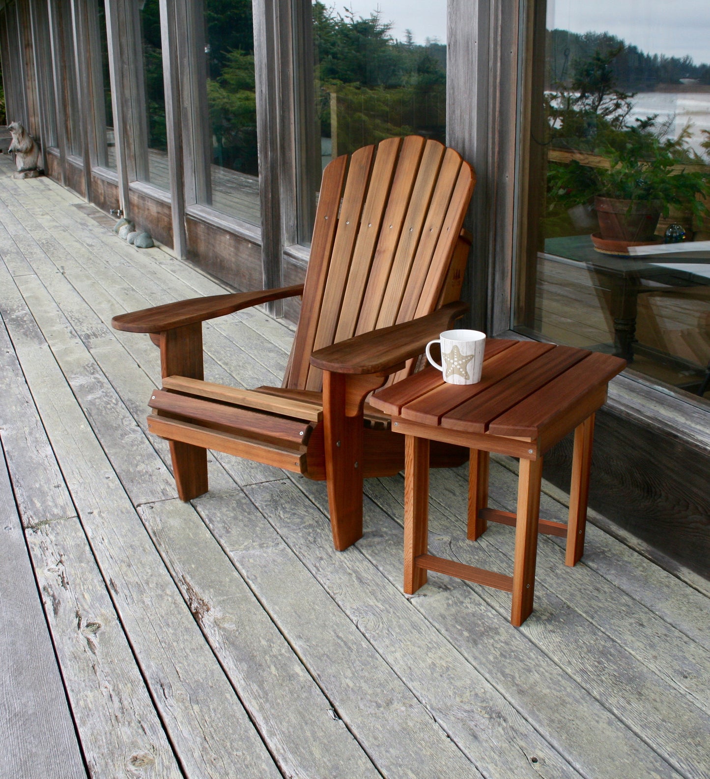 Western Red Cedar Adirondack chair with matching side table and mug on a weathered wood deck