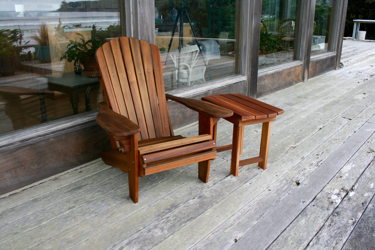 Western Red Cedar Adirondack chair and matching side table viewed from the front on a weathered deck