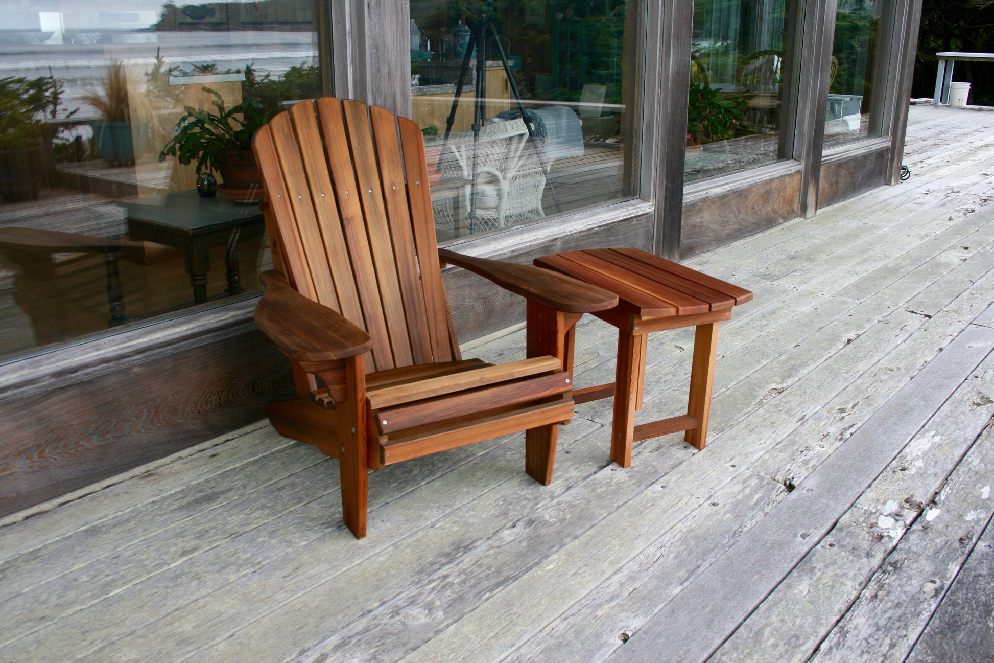 Western Red Cedar Adirondack chair and matching side table viewed from the front on a weathered deck
