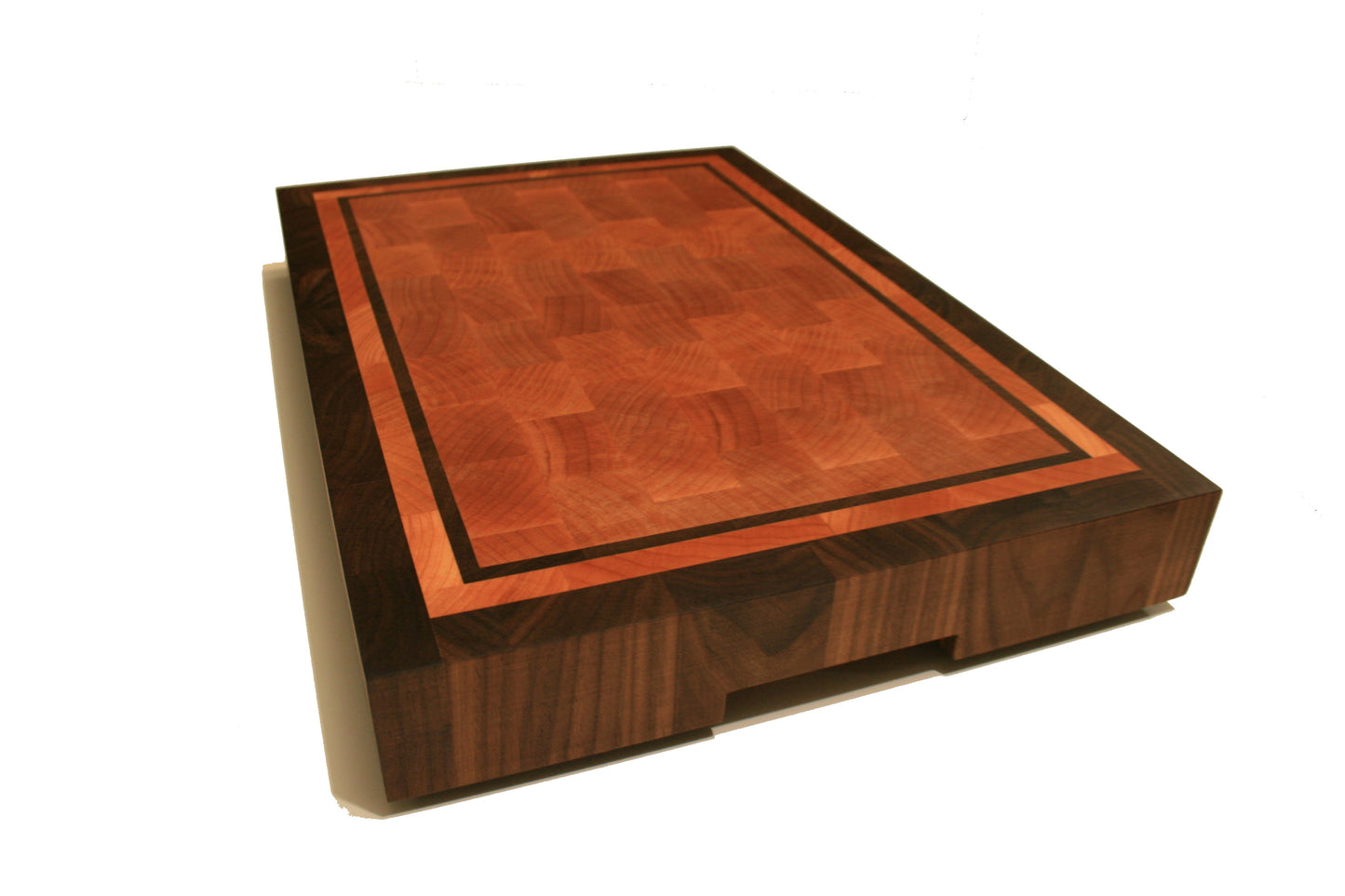 Angled view of the bordered end-grain cutting board showing its thickness and recessed handhold