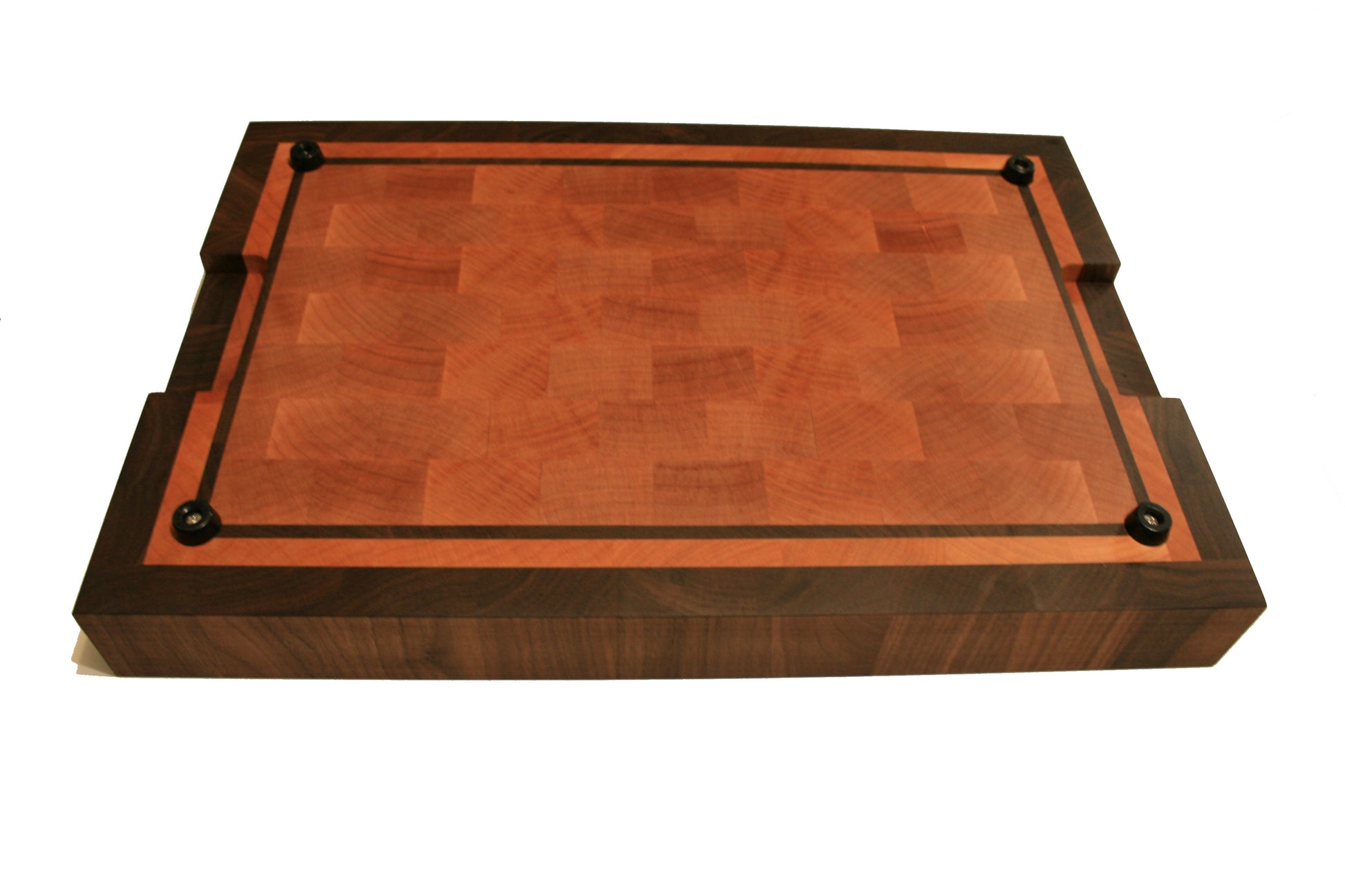 Underside of the bordered end-grain cutting board showing four rubber feet and recessed handholds