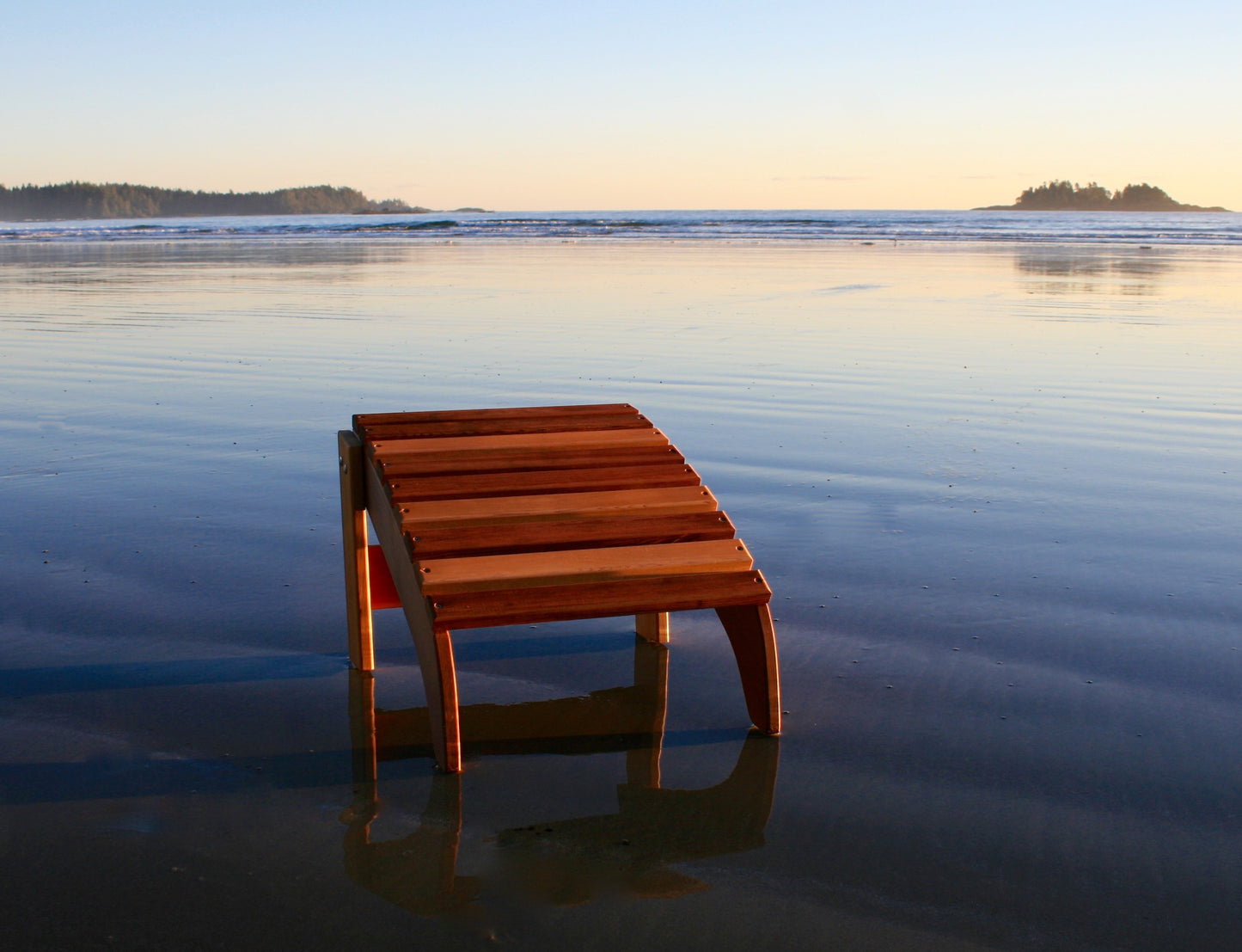 Front view of a Western Red Cedar Adirondack footrest on wet sand