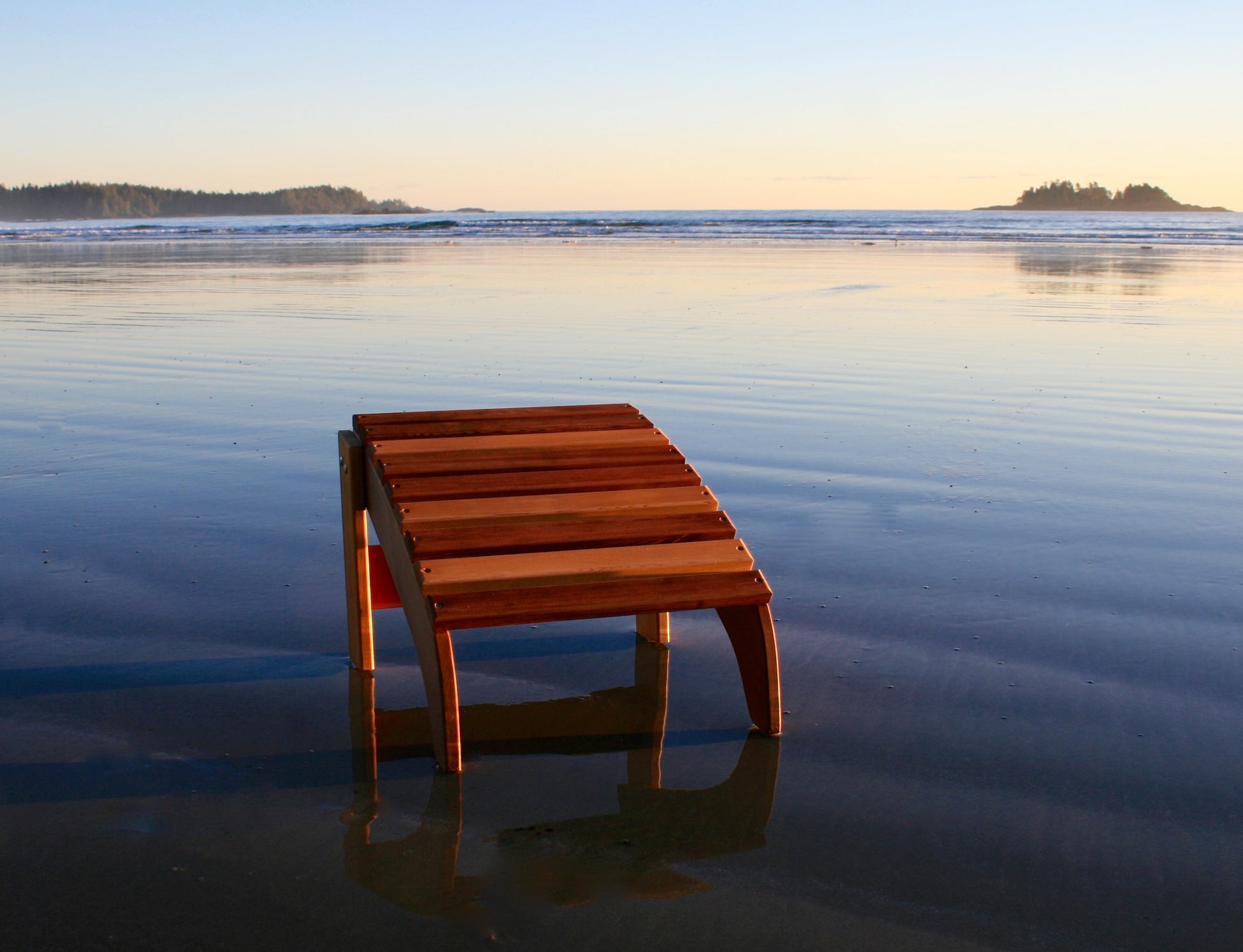 Front view of a Western Red Cedar Adirondack footrest on wet sand