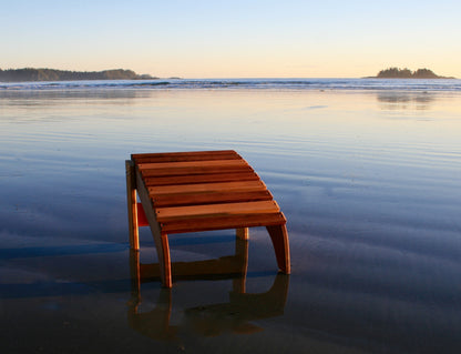 Front view of a Western Red Cedar Adirondack footrest on wet sand