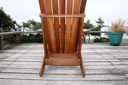 Rear view showing the back-slat construction, lower support brace and leg stance on a weathered deck