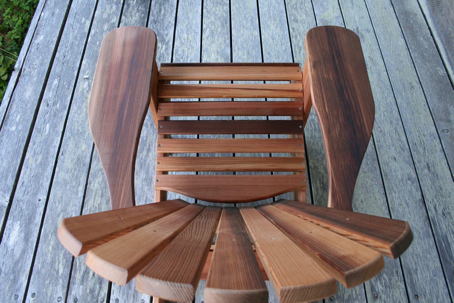 Top view showing the curved seat slats, broad arms and natural colour variation in the cedar